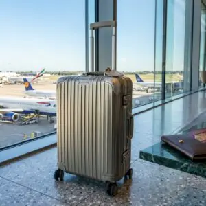 Premium champagne silver carry-on suitcase beside passport at an international airport lounge